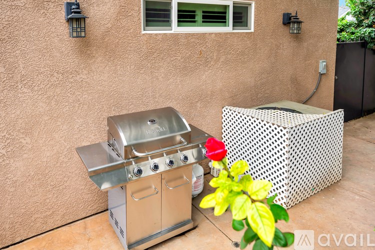A red rose sits on a grill next to a planter.