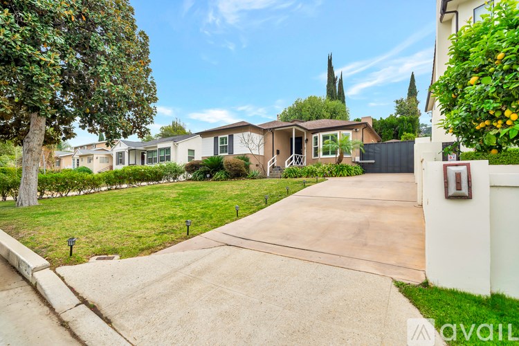 A house with a driveway and a white fence is for sale.
