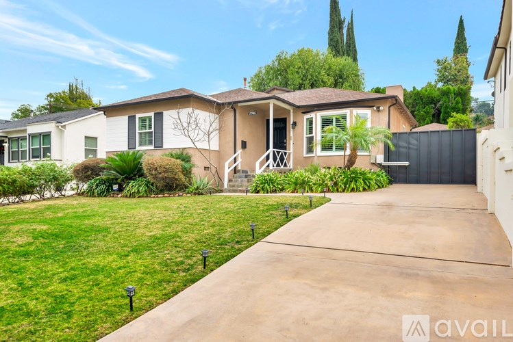 A house with a driveway and a fence in front of it.