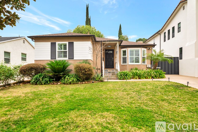 A house with a green plant on the roof and a black gate.