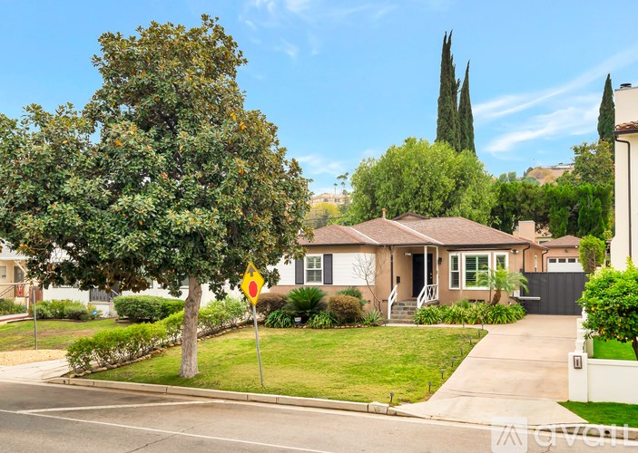 A yellow sign is on a pole in front of a house.