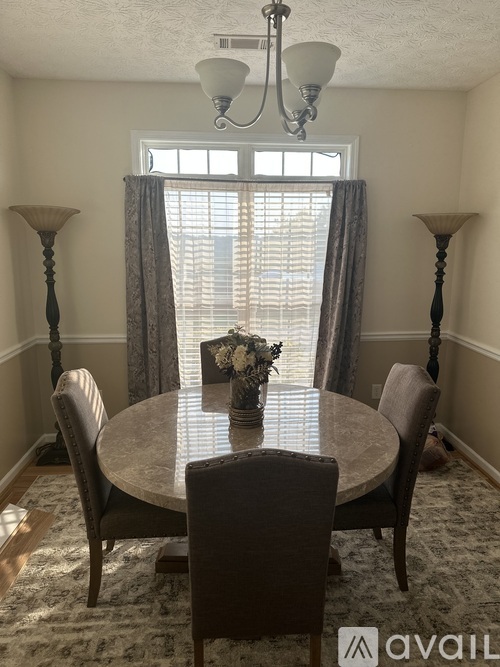 A dining room with a round table and chairs.
