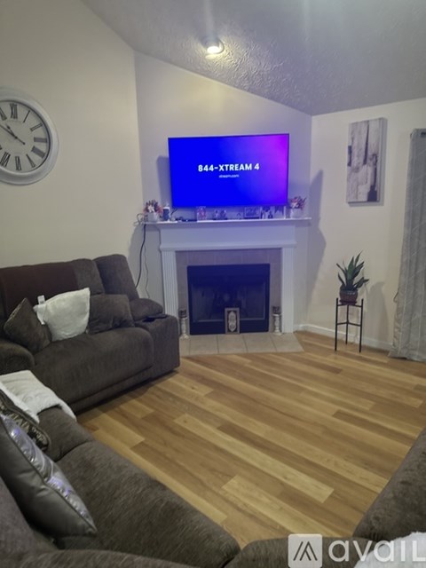 A living room with a grey couch and a purple TV displaying the number 844.
