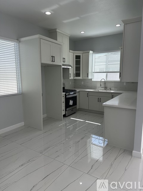 A kitchen with white cabinets and a white floor.