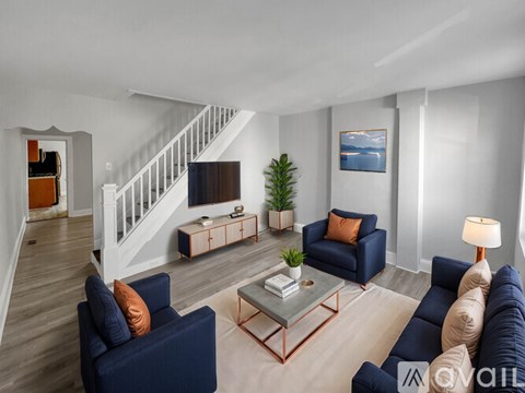 A living room with a staircase and a painting of a lake.