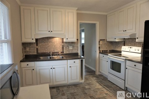 A kitchen with white cabinets and black countertops.