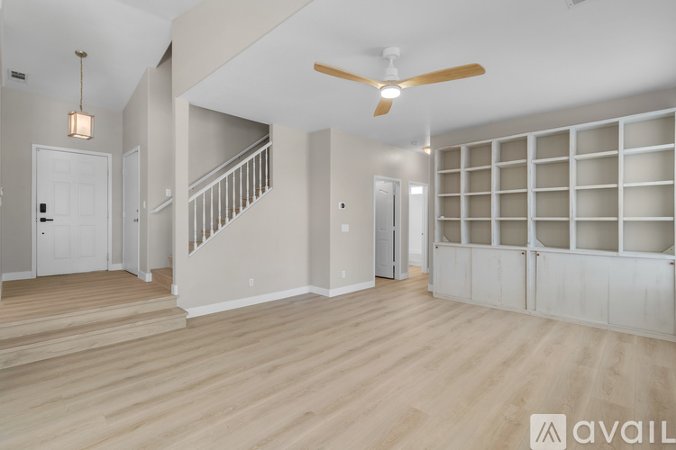 A spacious room with a staircase and a ceiling fan.
