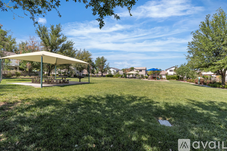 A grassy park with a canopy and picnic tables.