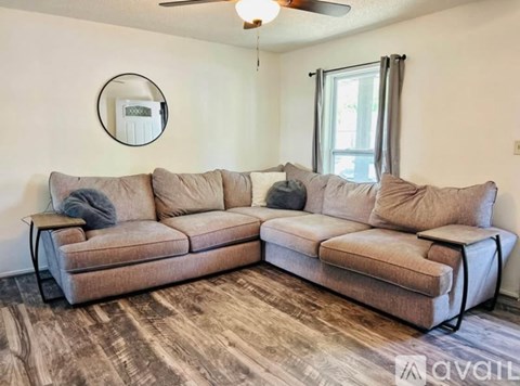 A living room with a beige sofa and a round mirror on the wall.