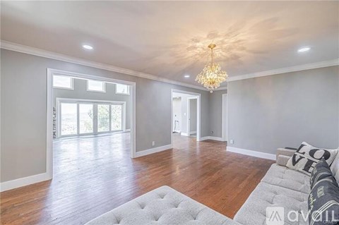A spacious living room with a grey sofa and a chandelier.