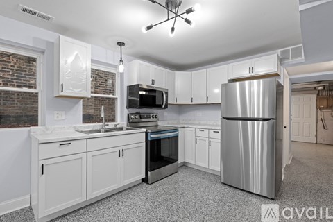A kitchen with white cabinets and a stainless steel refrigerator.