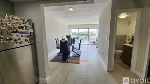 A kitchen with a refrigerator covered in magnets and a living room with a couch and a coffee table.