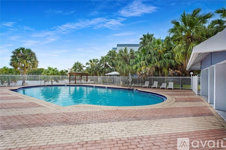 A pool surrounded by a brick patio and palm trees.