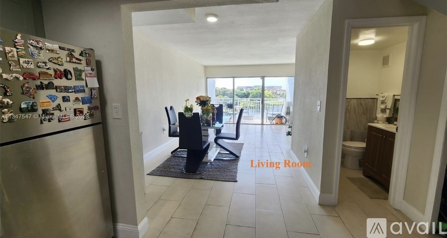 A kitchen with a refrigerator covered in magnets and a view of the outdoors through a window.