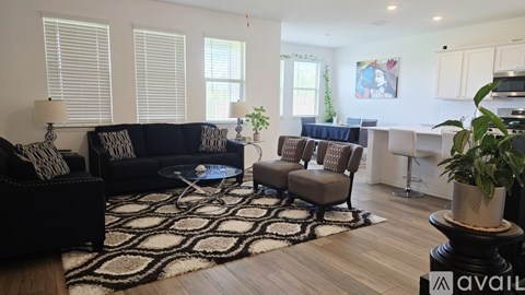 A living room with a black couch and a rug.