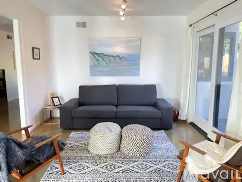 A living room with a grey sofa and a rug.