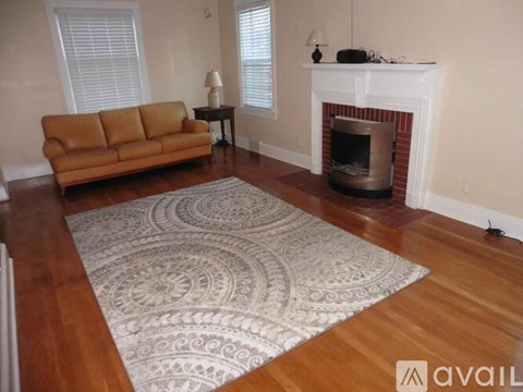 A living room with a fireplace and a rug on the floor.