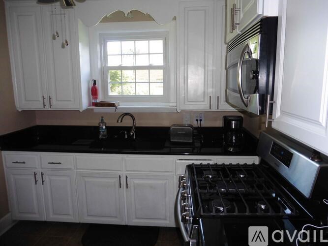 A kitchen with white cabinets and a black countertop.
