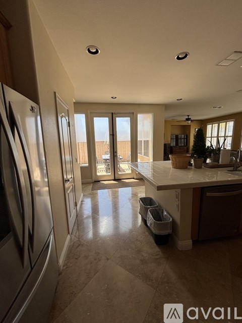 A kitchen with a refrigerator on the left and a dining area in the background.