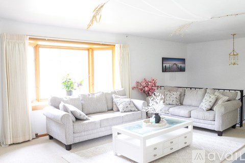 A living room with a grey couch, a white coffee table, and a painting on the wall.