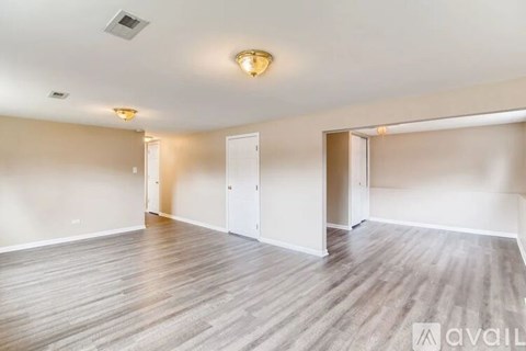 A spacious room with wooden flooring and white walls.