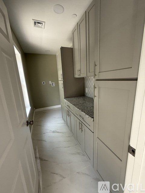 A kitchen with white cabinets and a marble floor.