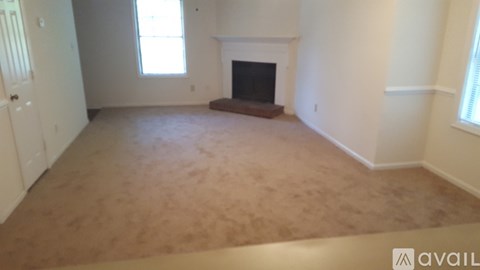 A living room with a fireplace and carpeted floor.