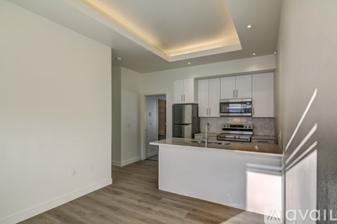 A modern kitchen with white cabinets and a wooden floor.