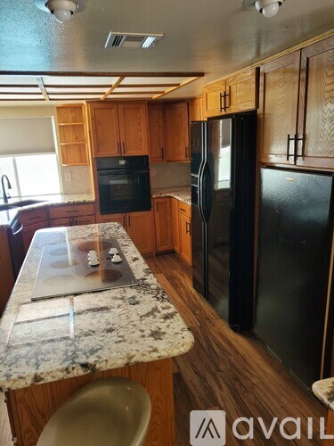 A kitchen with a granite counter top and wooden cabinets.