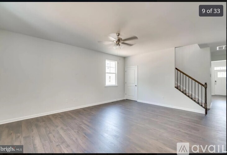 A spacious room with wooden flooring and a ceiling fan.