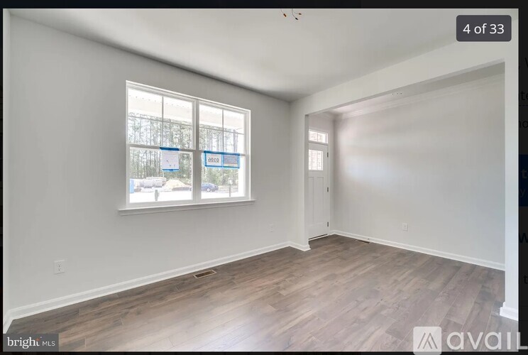 A room with a window showing a view of a fence and trees.