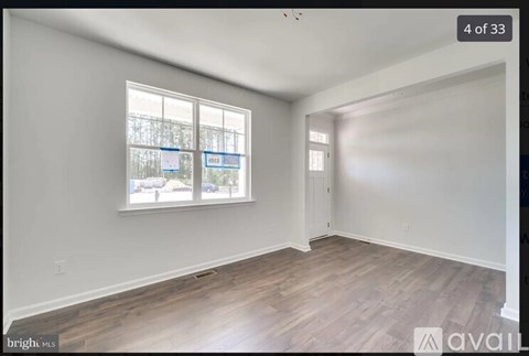A room with a window showing a view of a fence and trees.