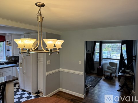 A chandelier hangs over a kitchen island with a checkered floor.