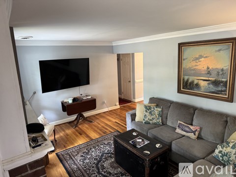A living room with a grey couch, a coffee table, and a painting on the wall.