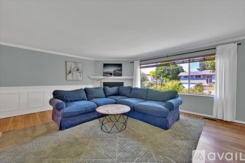 A blue couch is in a living room with a white coffee table in front of it.