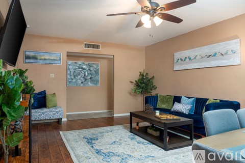 A living room with a blue couch and a ceiling fan.