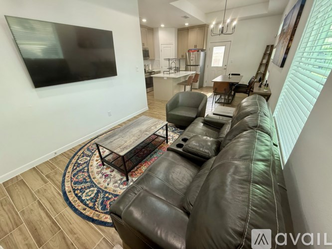 A living room with a leather couch and a flat screen TV mounted on the wall.