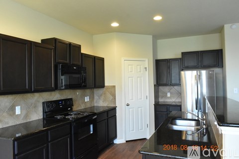 A kitchen with black cabinets and a stove top oven.
