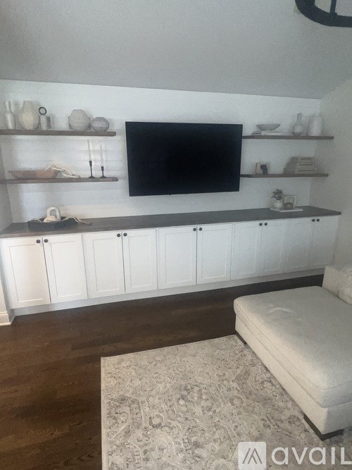 A living room with a television, shelves, and a couch.