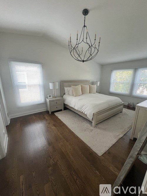 A bedroom with a large bed and a chandelier.