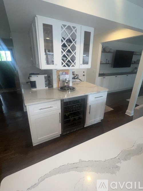 A kitchen with white cabinets and a wooden floor.