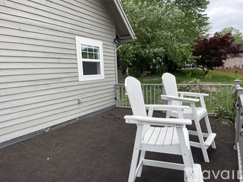 Three white chairs are on a porch.