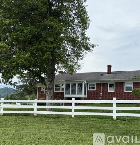 A house with a white fence and a tree in front of it.