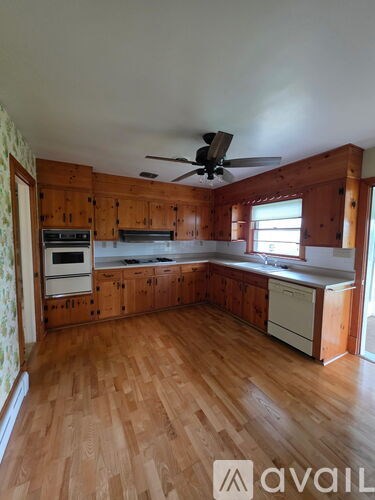 A kitchen with wooden cabinets and a ceiling fan.