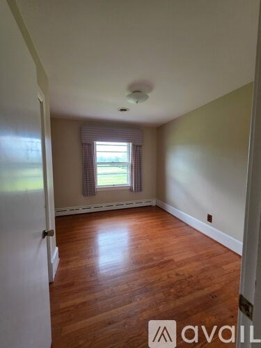 A room with wooden floors and a window with a view of the grass.