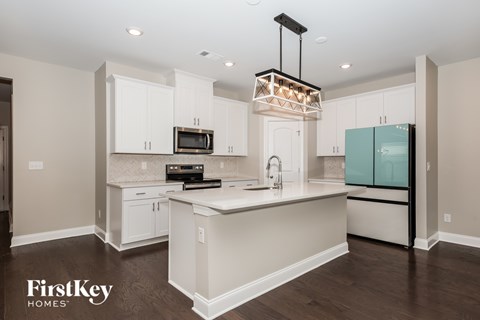 A kitchen with a white island and a black stove top oven.