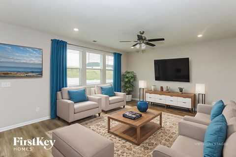 A living room with a ceiling fan, a couch, a chair, a coffee table, and a painting on the wall.