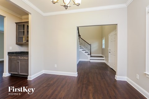 A spacious room with wooden floors and a staircase leading to another room.