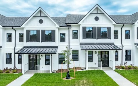 A white two-story house with black roofing and a black awning.