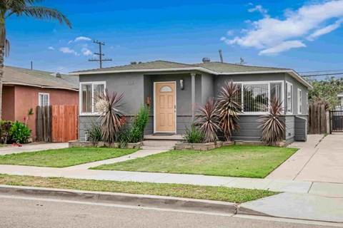 A house with a grey front yard and a brown fence.